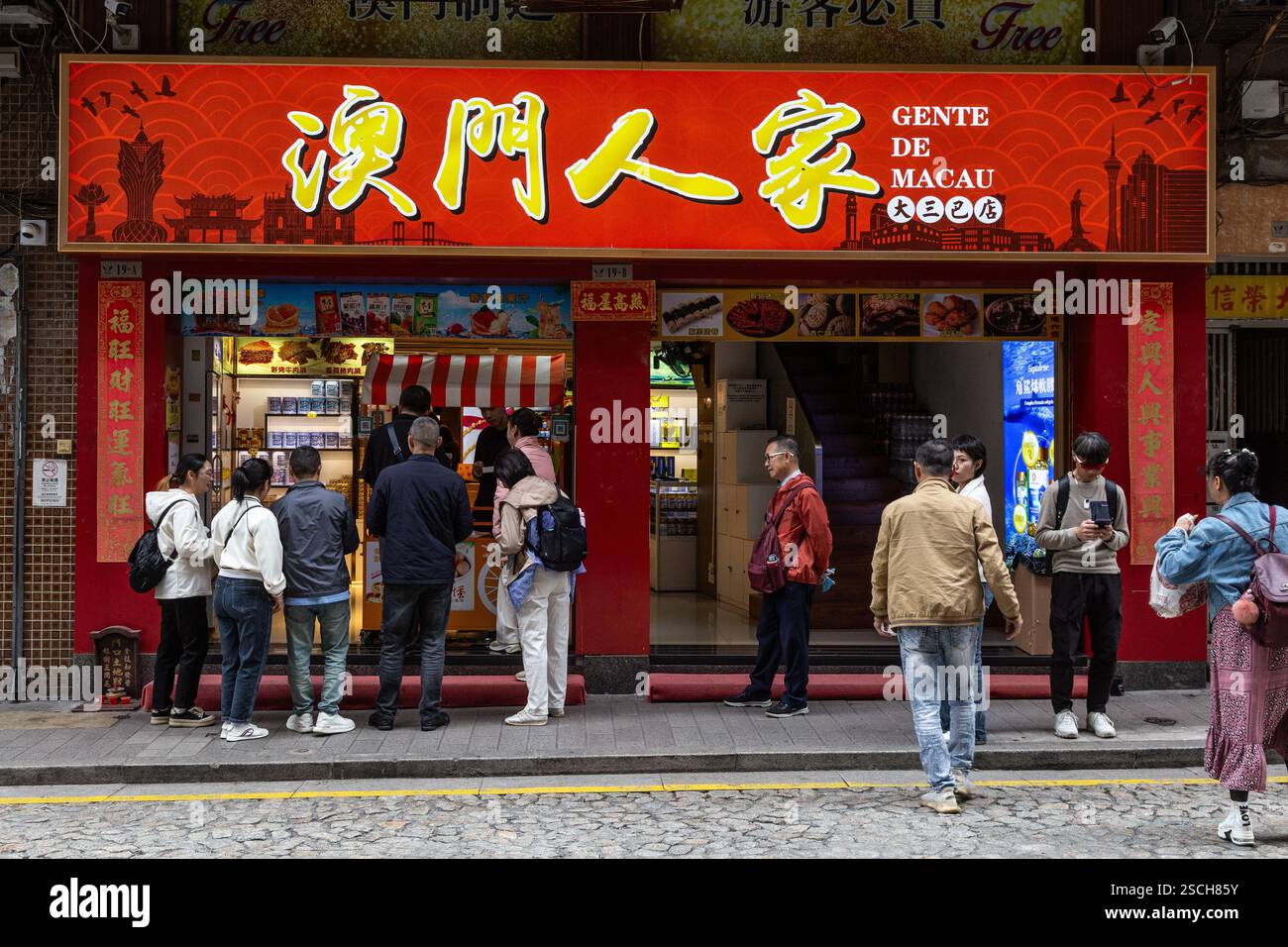 Turisti che comprano cibo di strada e crostate di uova a Macao Foto Stock