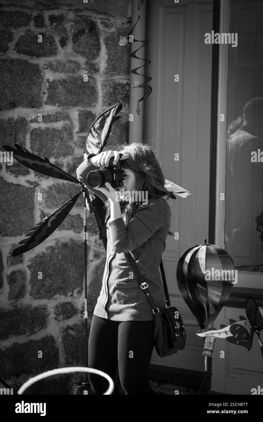 Una donna (probabilmente fotografa) scatta foto con la macchina fotografica, probabilmente di un edificio. Foto Stock