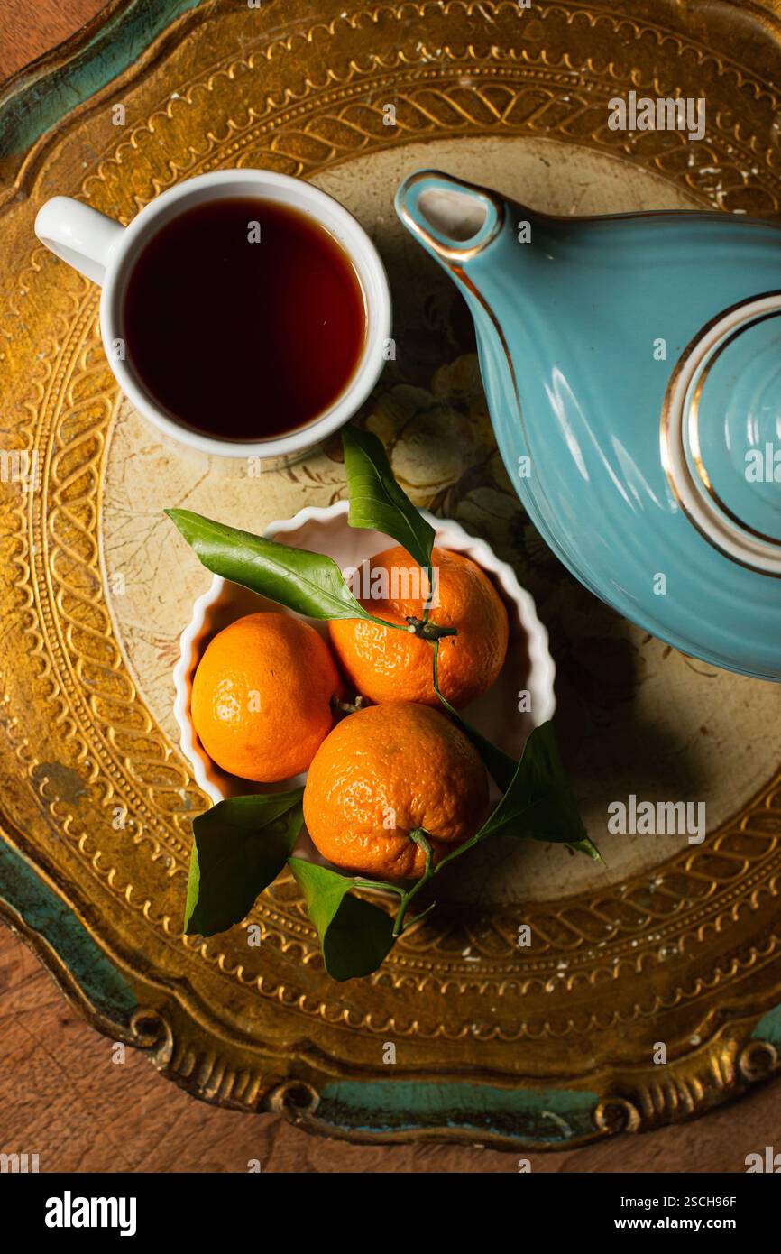 Teiera blu, tazza e arance sul piatto Foto Stock