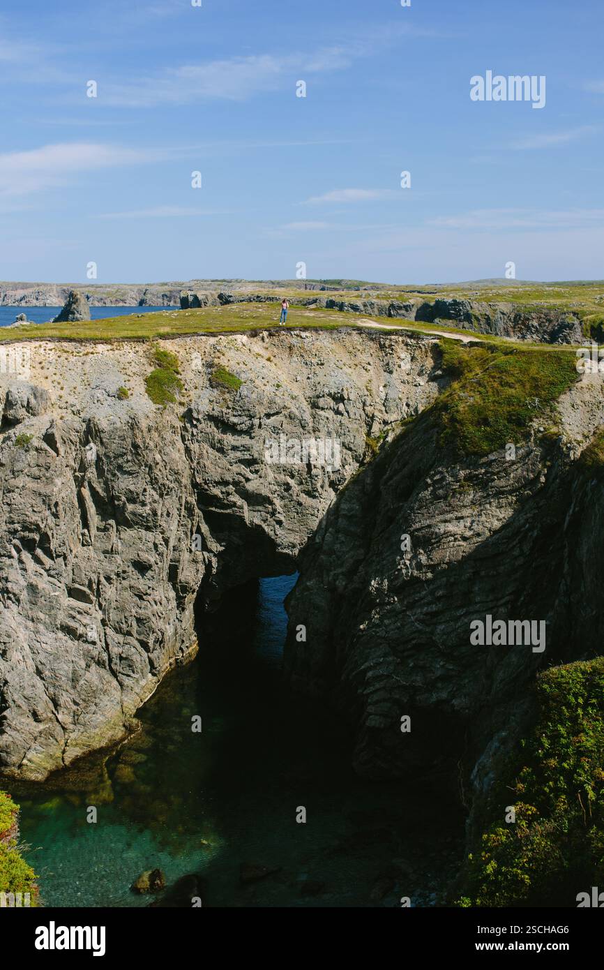 Una donna irriconoscibile si erge sulle scogliere panoramiche che si affacciano sull'oceano al Dungeon Provincial Park, Newfoundland & Labrador, Canada. Il captu della foto Foto Stock