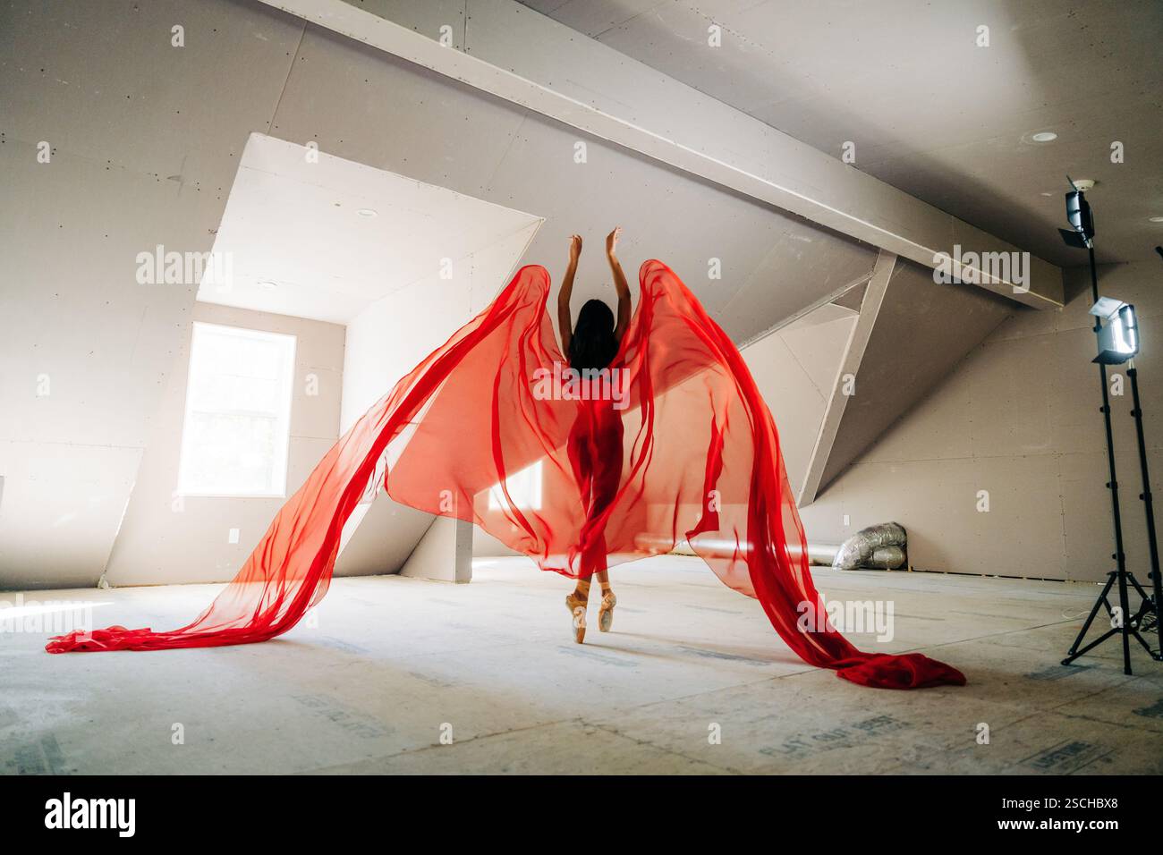 Ballerina in tessuto rosso che salta con grazia, tessuto che ricorda le ali Foto Stock