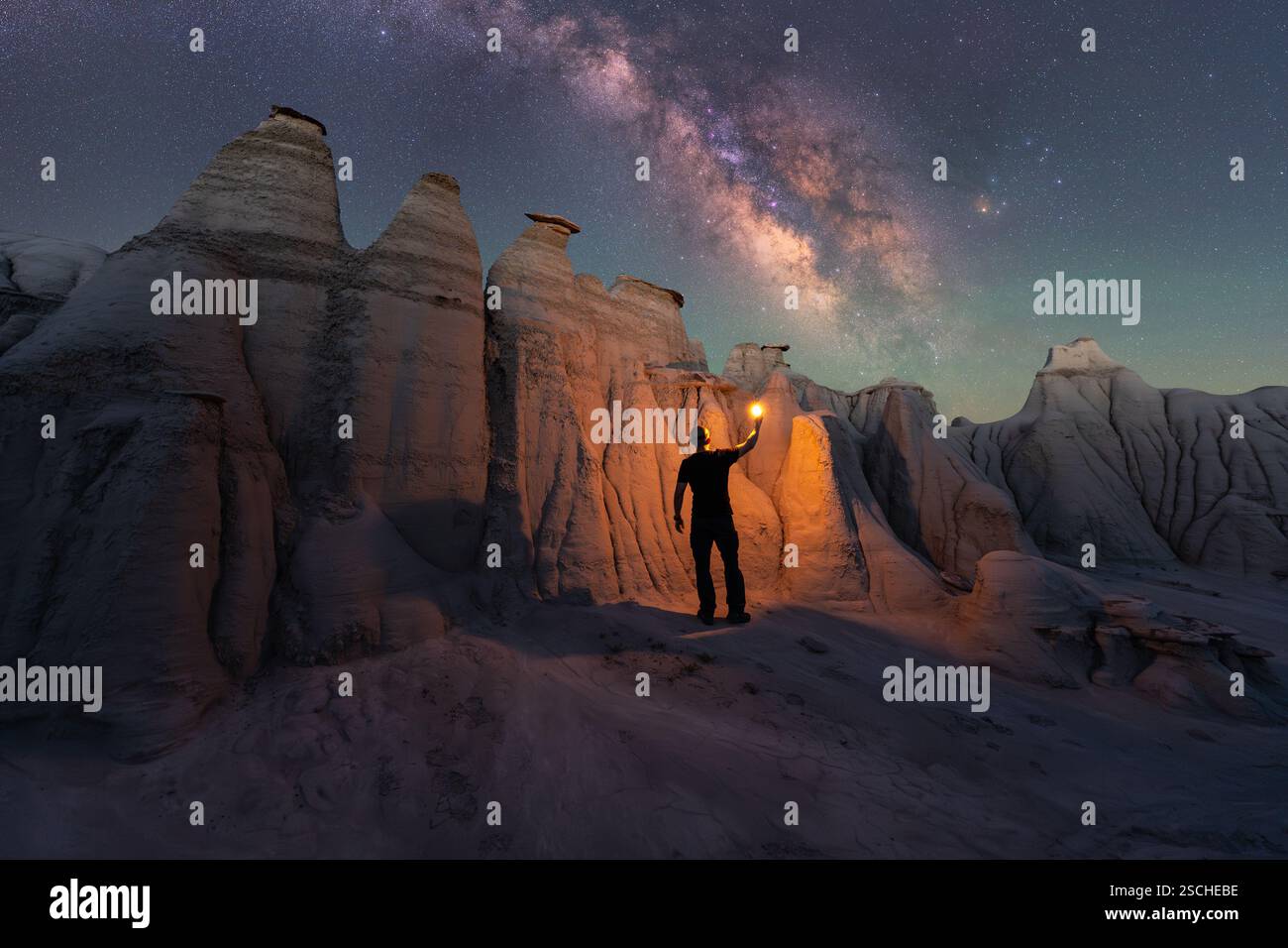 Una figura solitaria illumina le magnifiche formazioni di arenaria del Goblin Valley State Park, Utah, sotto un cielo stellato mozzafiato, evidenziando il mi Foto Stock
