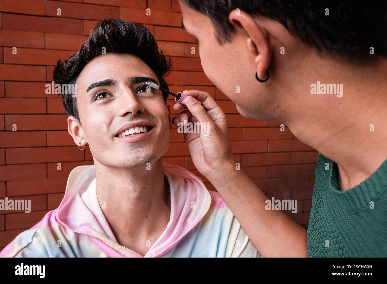 Una coppia amorevole, con uno che applica il trucco alle ciglia dell'altro. Le loro espressioni gioiose e l'interazione morbida mettono in risalto l'amore e abbracciano l'individu Foto Stock