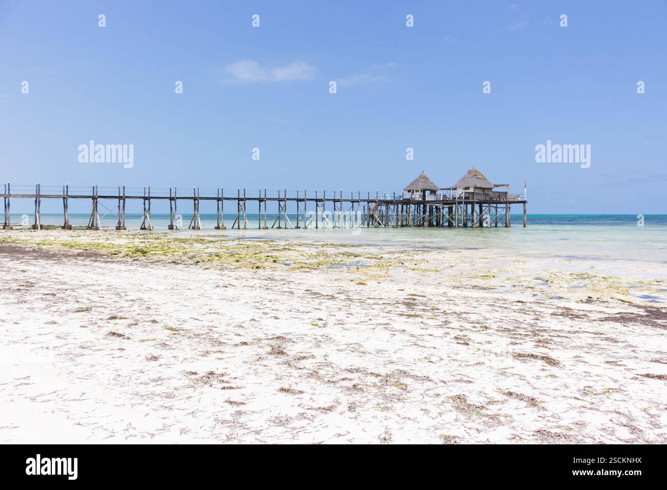 Molo in legno con capanna sulla spiaggia nelle giornate di sole. Bassa marea dell'Oceano Indiano. Idilliaco resort esotico. Molo in prospettiva con bungalow. Paradiso tropicale. Foto Stock