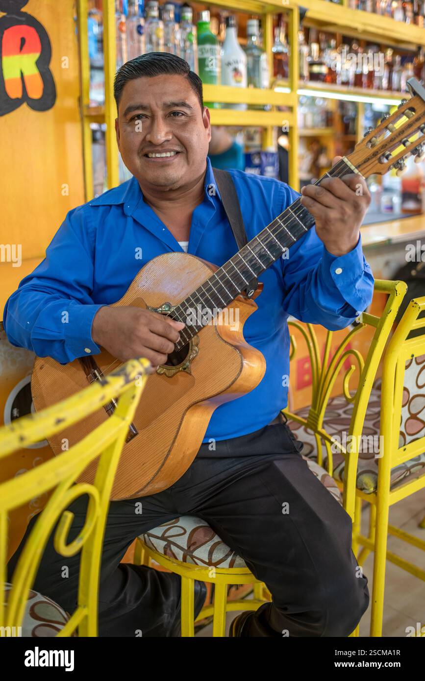 Chitarrista seduto su uno sgabello giallo luminoso al Ground Zero Bar di Nuevo Progreso, Tamaulipas, municipalità di Río Bravo, Messico. Foto Stock