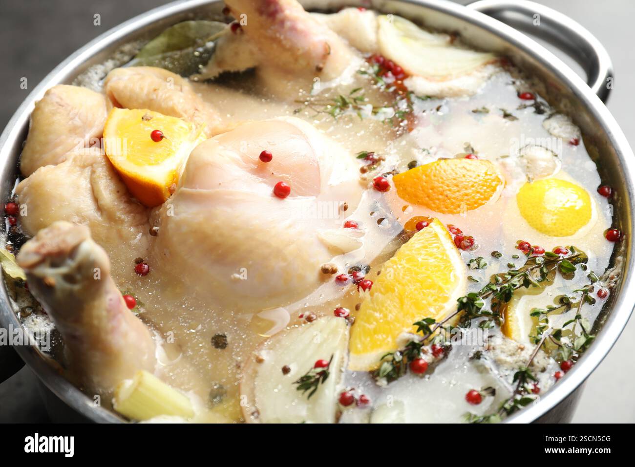 tacchino intero, agrumi tagliati e spezie in pentola sulla tavola, primo piano Foto Stock