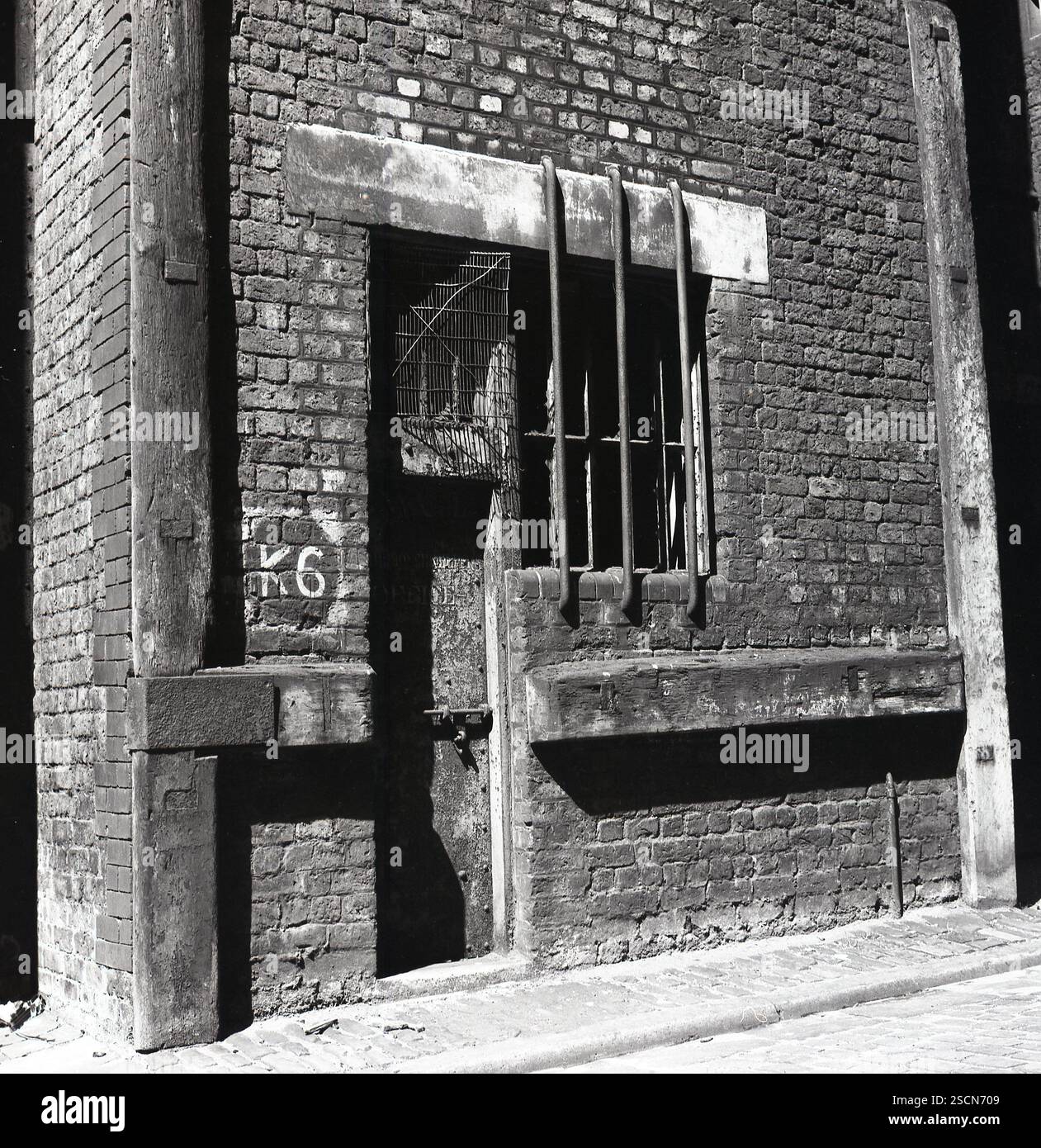 1969, storico edificio sul retro del vecchio molo in un vicolo acciottolato, K6 scritto sul muro accanto alla porta vecchia, barre d'acciaio coprono la finestra posteriore, Liverpool, Inghilterra, Regno Unito. Foto Stock