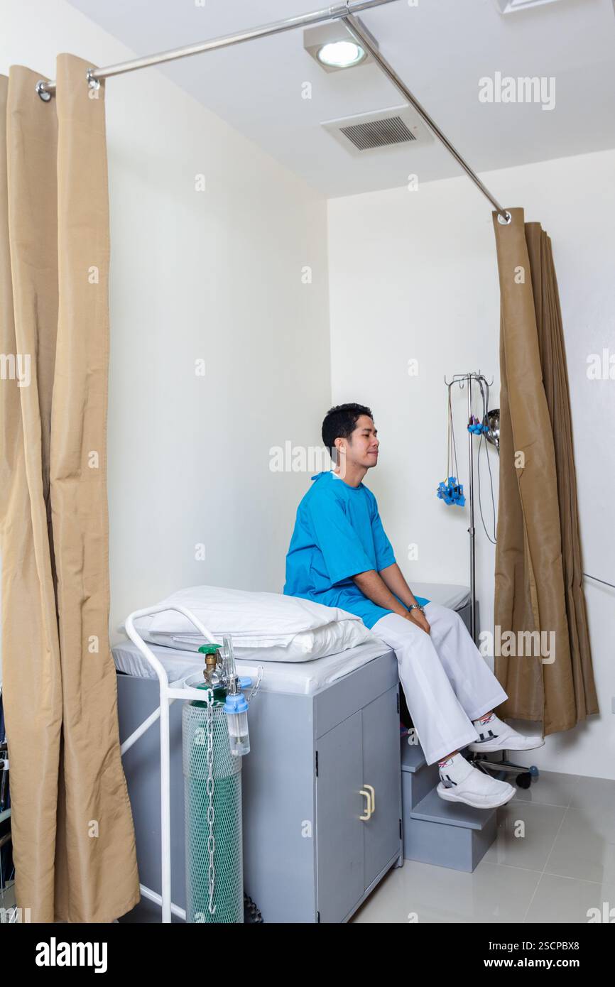 Un paziente di sesso maschile filippino attende il suo controllo medico in una clinica locale a Baguio City, Filippine, che offre servizi sanitari essenziali Foto Stock