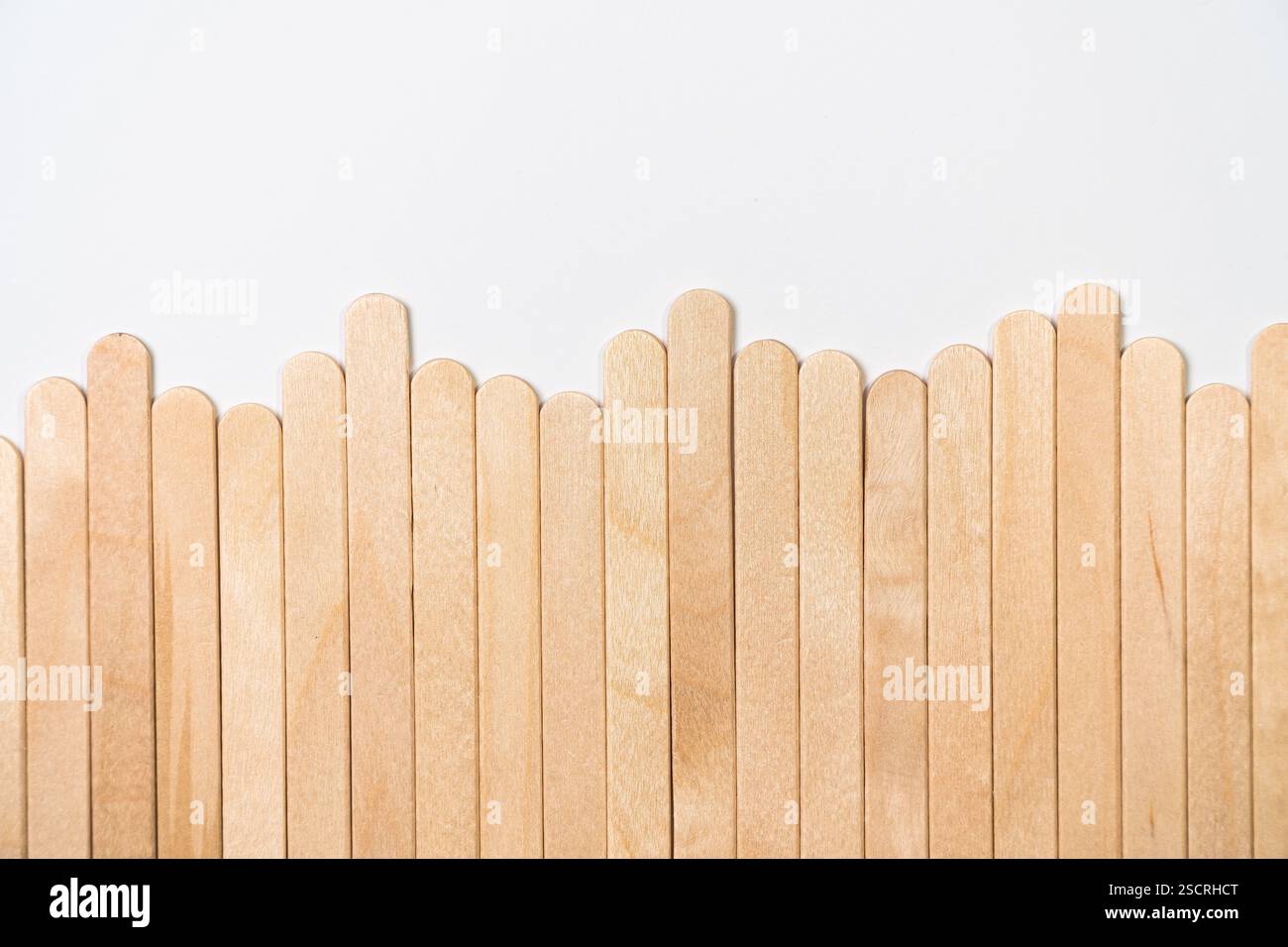 Recinzione in legno minimale realizzata con bastoncini di papavero su sfondo bianco Foto Stock