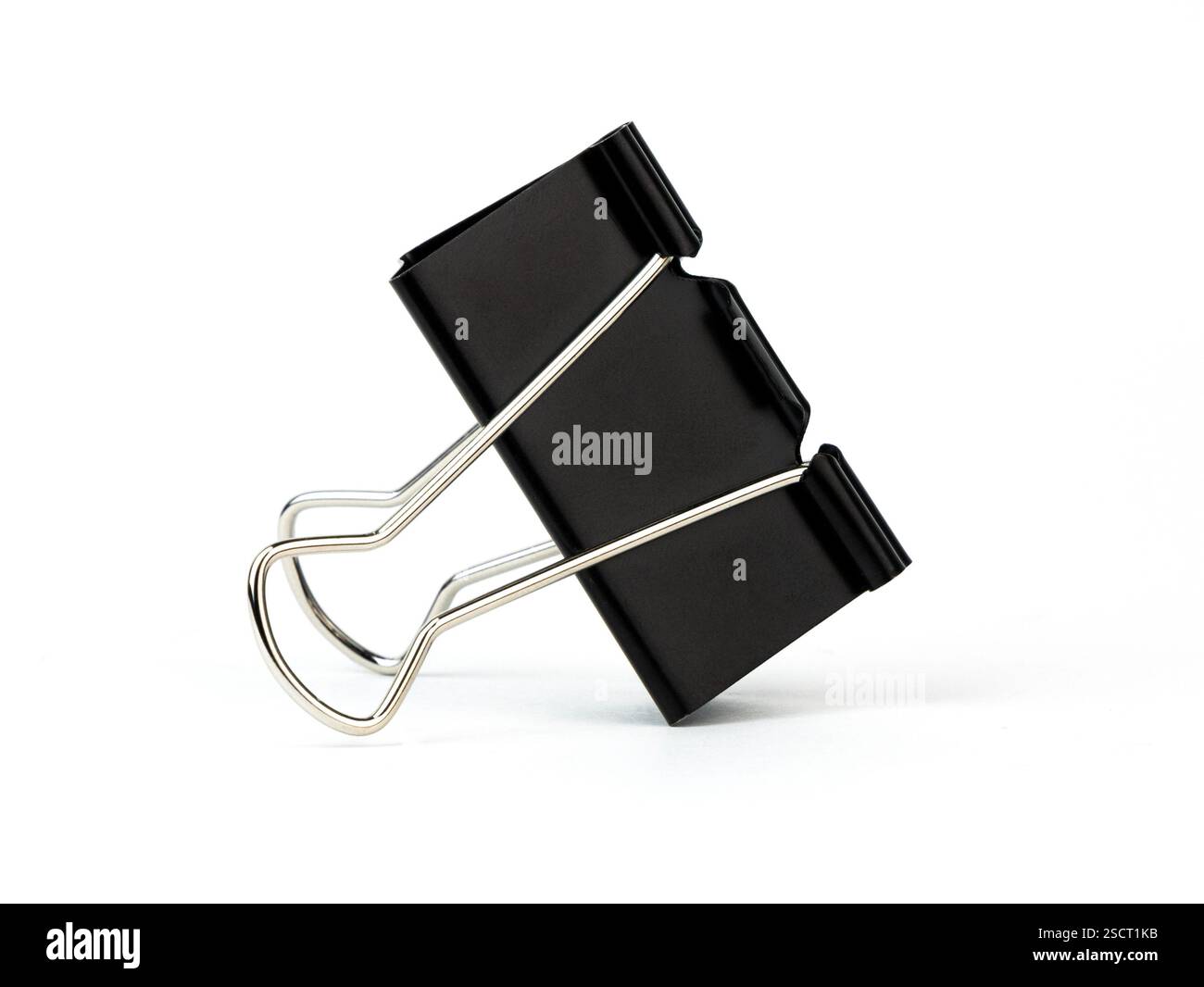 Una clip di legatura nera si appoggia su uno sfondo bianco Foto Stock