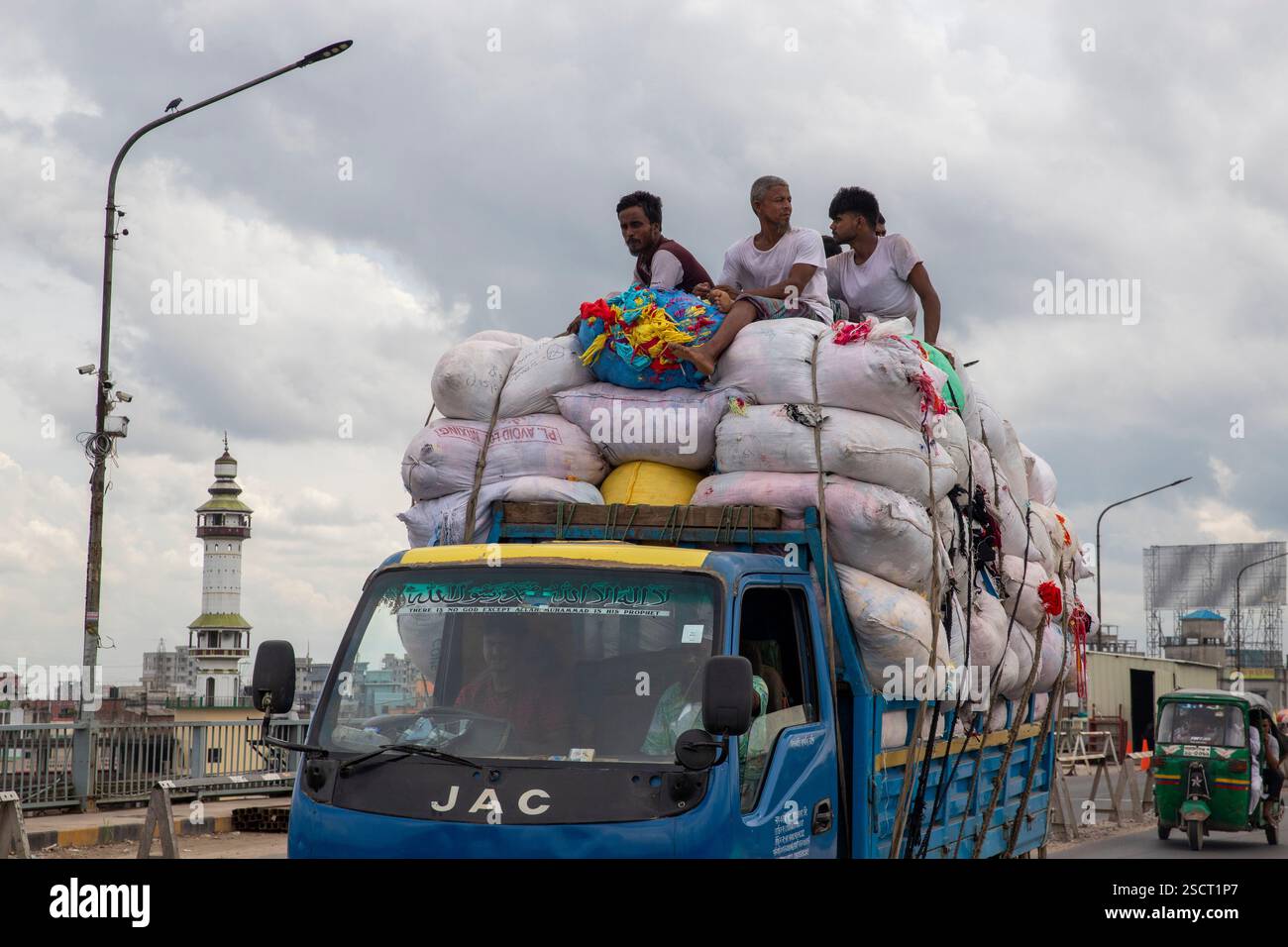 I lavoratori viaggiano sulla cima di un camion carico, rischiando la vita, Dacca, Bangladesh. Foto Stock