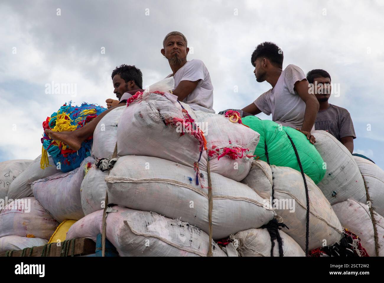 I lavoratori viaggiano sulla cima di un camion carico, rischiando la vita, Dacca, Bangladesh. Foto Stock