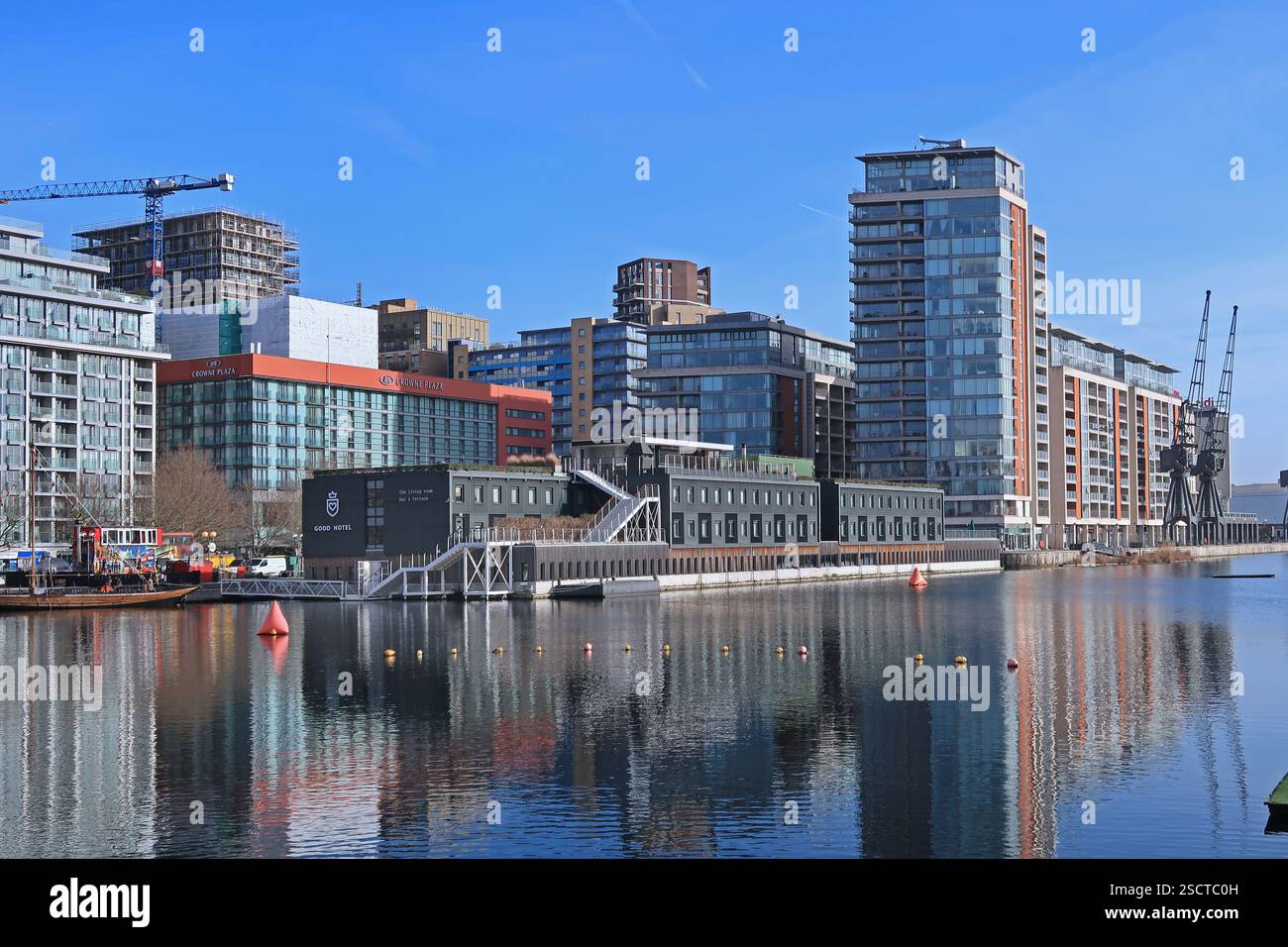 Nuovi edifici sul lato nord del Royal Victoria Dock, Londra, Regno Unito. Include hotel, uffici e appartamenti. Mostra le vecchie gru portuali all'estrema destra. Foto Stock