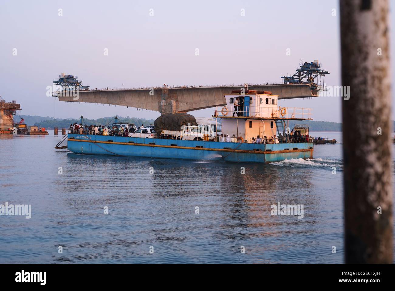 Una vista panoramica di un ponte strallato in costruzione al tramonto, con una luce dorata che si riflette sulle calme acque del fiume. Il tranquillo paesaggio controverso Foto Stock