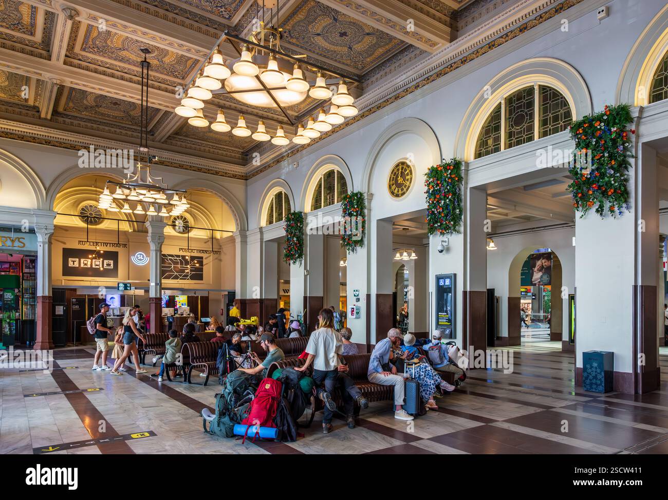 I passeggeri attendono un treno seduto sulle panchine nella sala d'ingresso della stazione centrale di Stoccolma, Svezia. Foto Stock