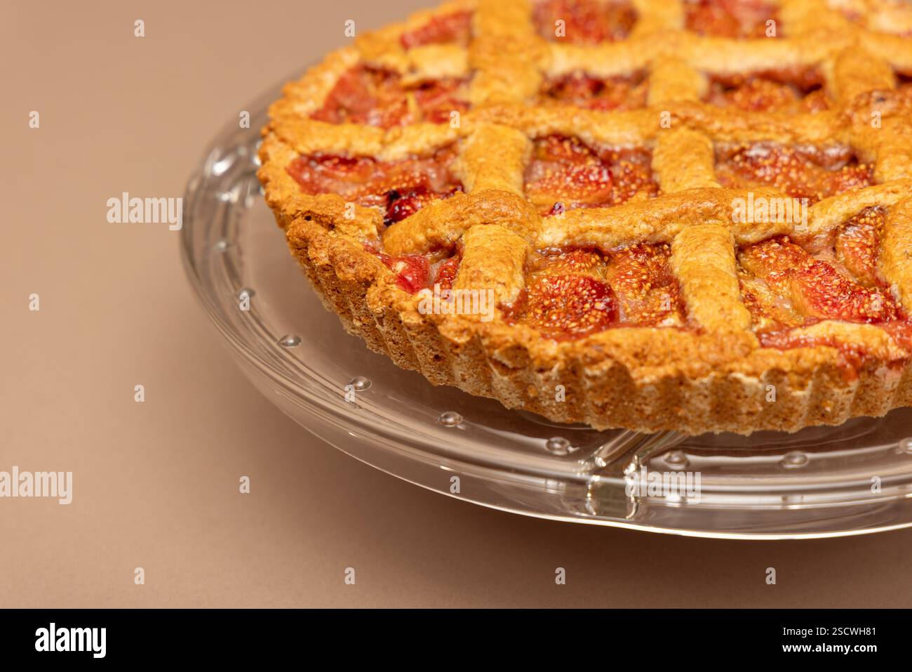 Crostata di fichi in stile italiano con un design croccante e ripieno succoso, cotta alla perfezione e servita su un piatto di vetro trasparente per una presentazione elegante Foto Stock