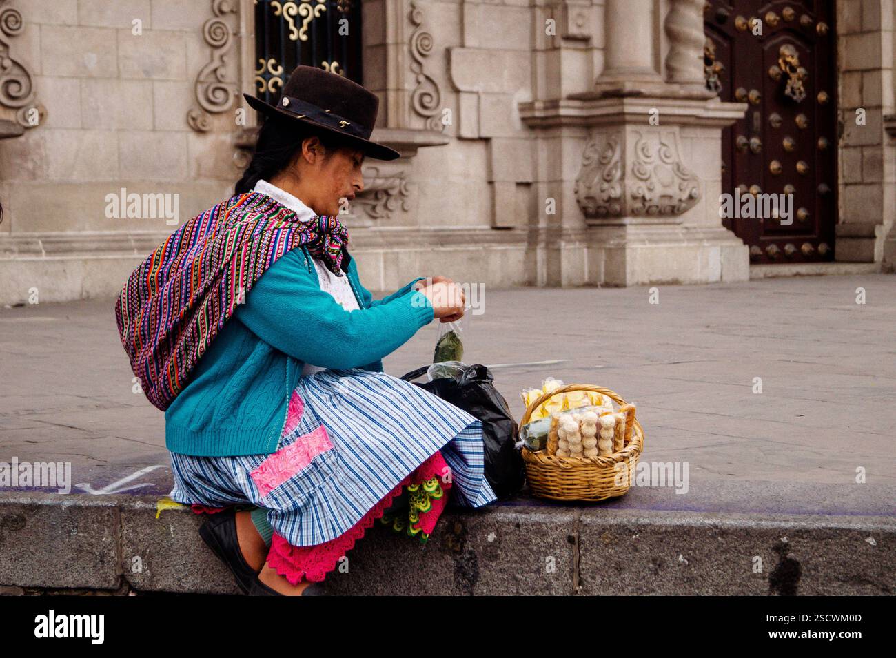 Venditore di strada di abbigliamento tradizionale andino che vende spuntini - architettura coloniale, Centro de Lima Foto Stock