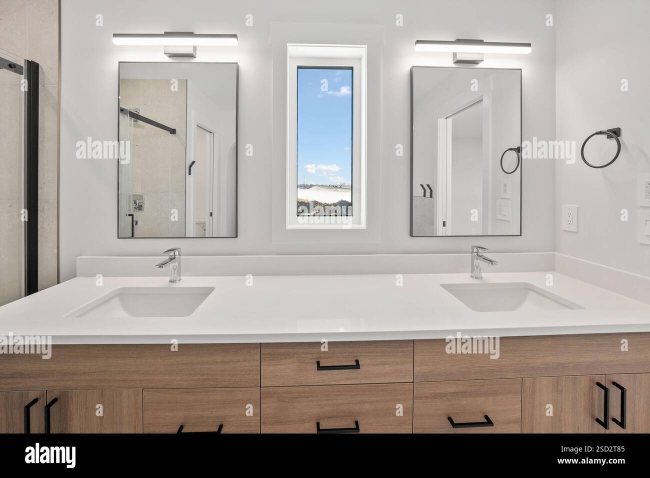 Il bagno era pulito e ben illuminato, con due lavandini e una finestra. Gli armadi e i ripiani in legno conferiscono al bagno un'atmosfera calda e invitante Foto Stock