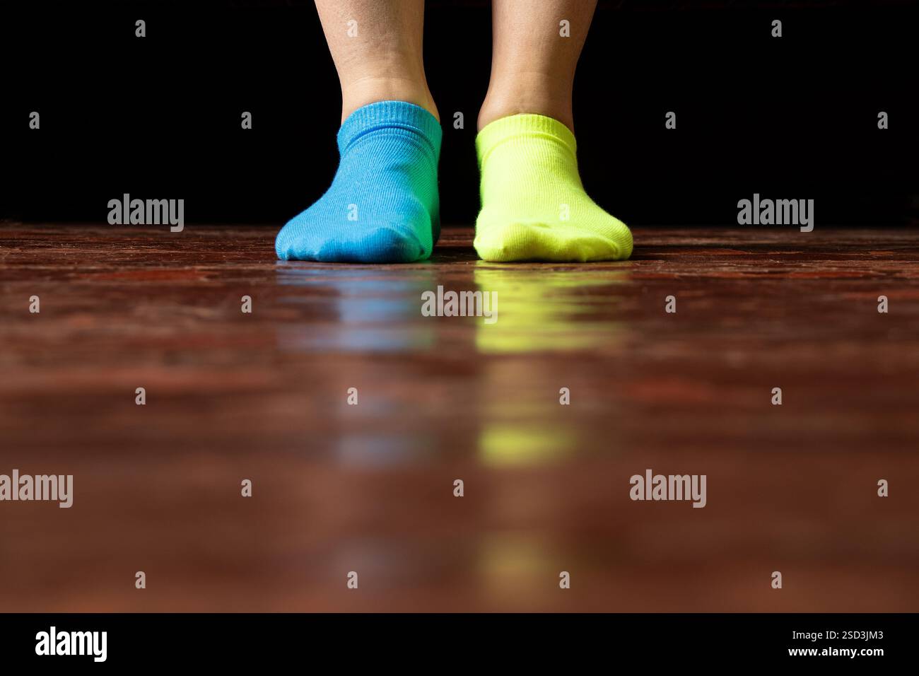 Gambe da donna in calze di diversi colori sul pavimento a casa seduta sul letto, gambe da donna Foto Stock