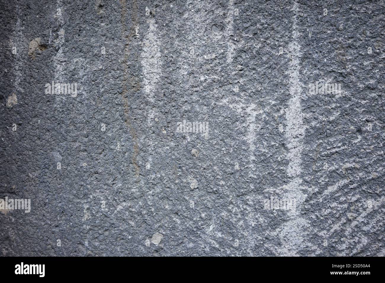 Una parete grigia testurizzata mostra imperfezioni naturali e una finitura ruvida. Varie sfumature e motivi creano un effetto visivo interessante, evidenziando Foto Stock