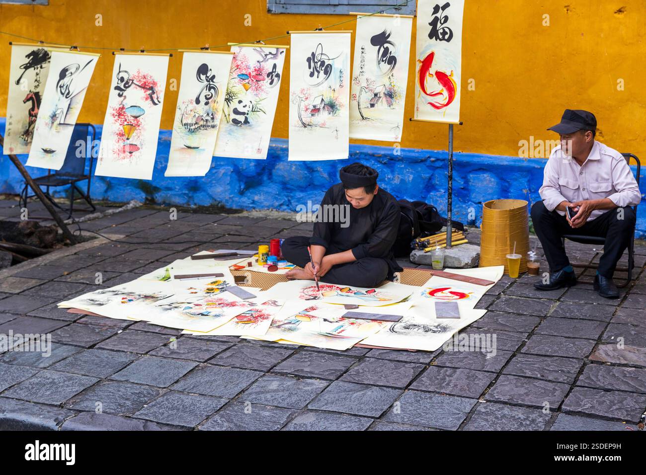 Un artista si è concentrato sulla creazione di intricate calligrafie mentre era seduto a terra Hoi An, Vietnam, mercoledì 6 novembre 2024. Foto Stock