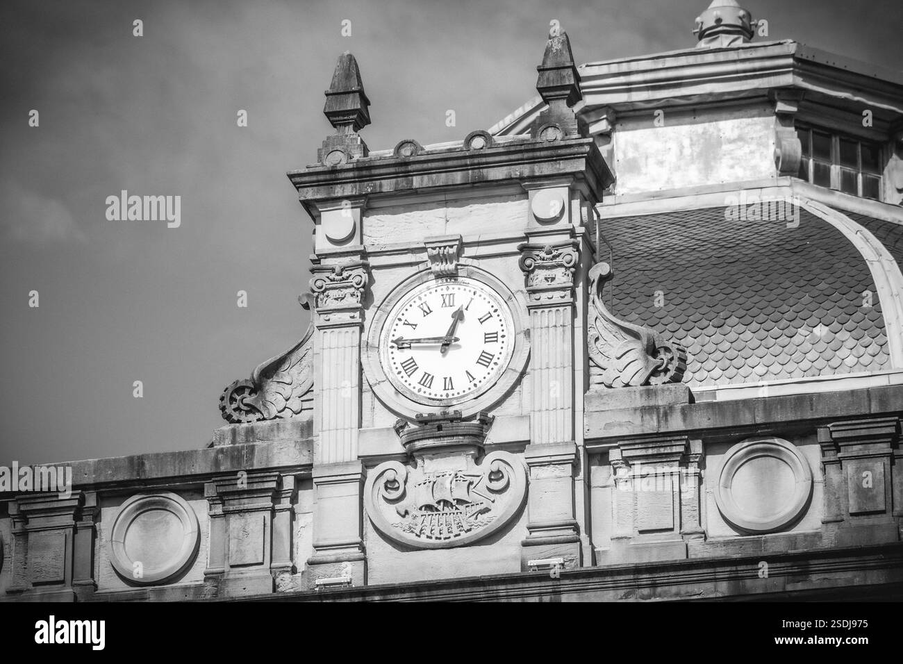 Immagine in bianco e nero di una torre dell'orologio ornata in cima a un edificio storico, che mostra intricati dettagli architettonici e design classico, San Sebastian Foto Stock