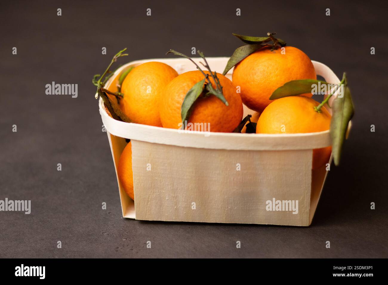 Primo piano di frutta mandarina in una scatola di legno su sfondo grigio Foto Stock