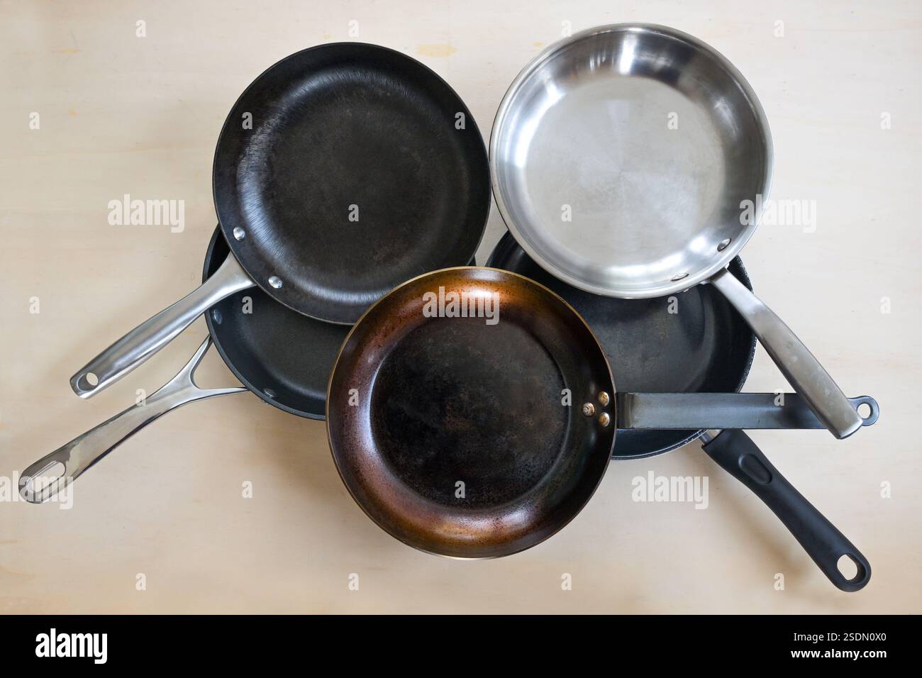 Selezione di padelle in vari materiali, acciaio inox, ghisa, acciaio al carbonio e rivestimento antiaderente in PTFE, vista dall'alto ad angolo alto, l Foto Stock