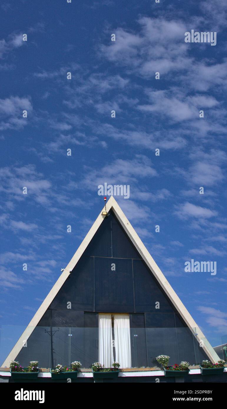 Facciata anteriore di una casa A-Frame su un cielo blu e sfondo di nuvole sparse Foto Stock