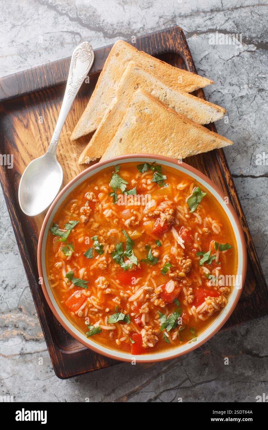 Zuppa di peperoni farciti fatta in casa, ricca di sapori di peperoni, cipolle, pomodori, manzo macinato e riso in primo piano nella ciotola sul tavolo. Verti Foto Stock