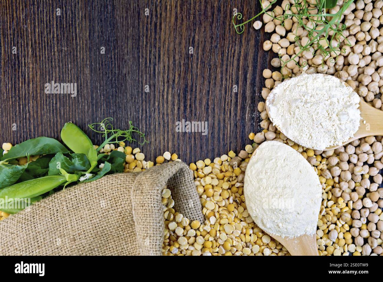 I ceci e farina di ceci in un cucchiaio, cialde di verde su sfondo di tela su tavola di legno Foto Stock