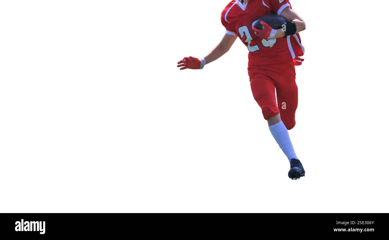 Un giovane giocatore di calcio in uniforme rossa corre abilmente con il calcio durante una partita. Foto Stock
