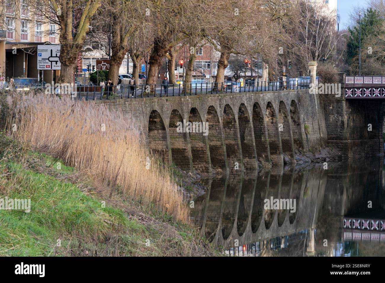 Gli archi di pietra dell'argine di Commercial Road si riflettono nel fiume Avon New Cut nel quartiere Redcliffe di Bristol. Foto Stock