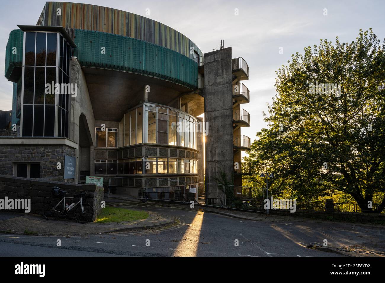 Il sole tramonta dietro il brutalista edificio Theatr Ardudwy ad Harlech, nel Galles del Nord. Foto Stock