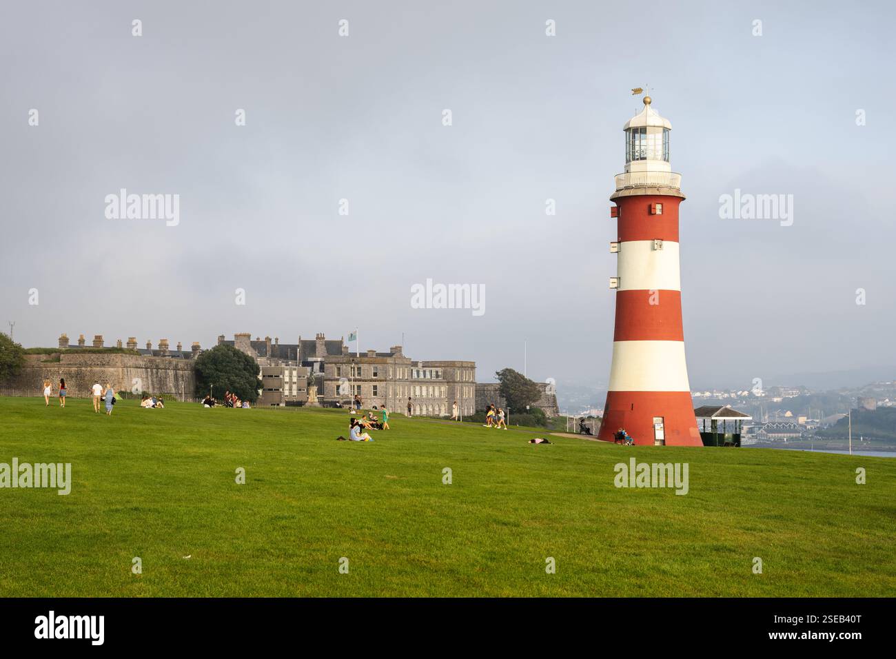 La gente passa davanti al faro della Smeaton's Tower sul parco Hoe di Plymouth, Devon. Foto Stock