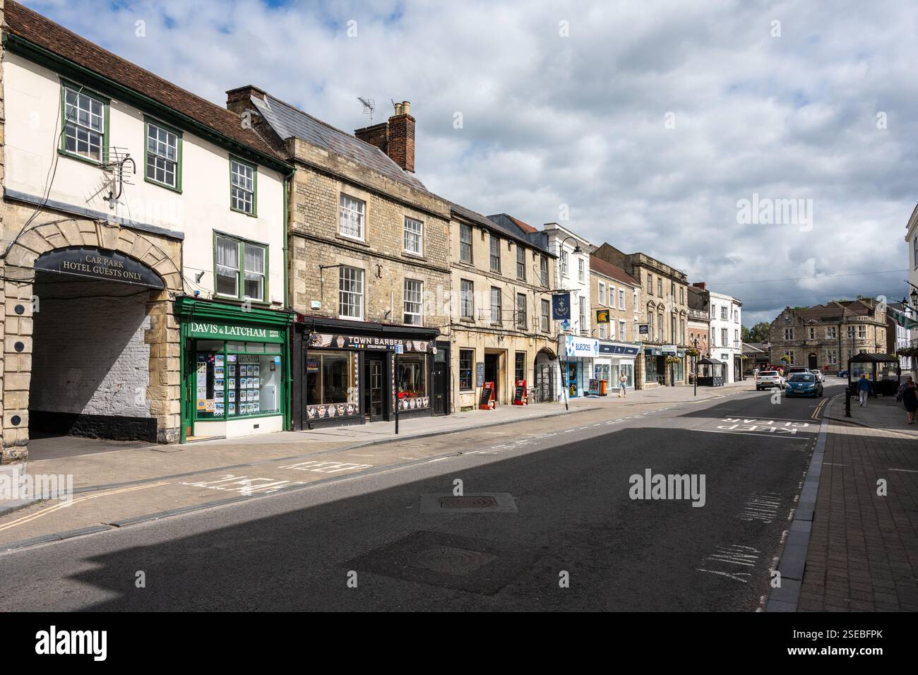 I pedoni passano accanto ai negozi della tradizionale High Street di Warminster nel Wiltshire. Foto Stock