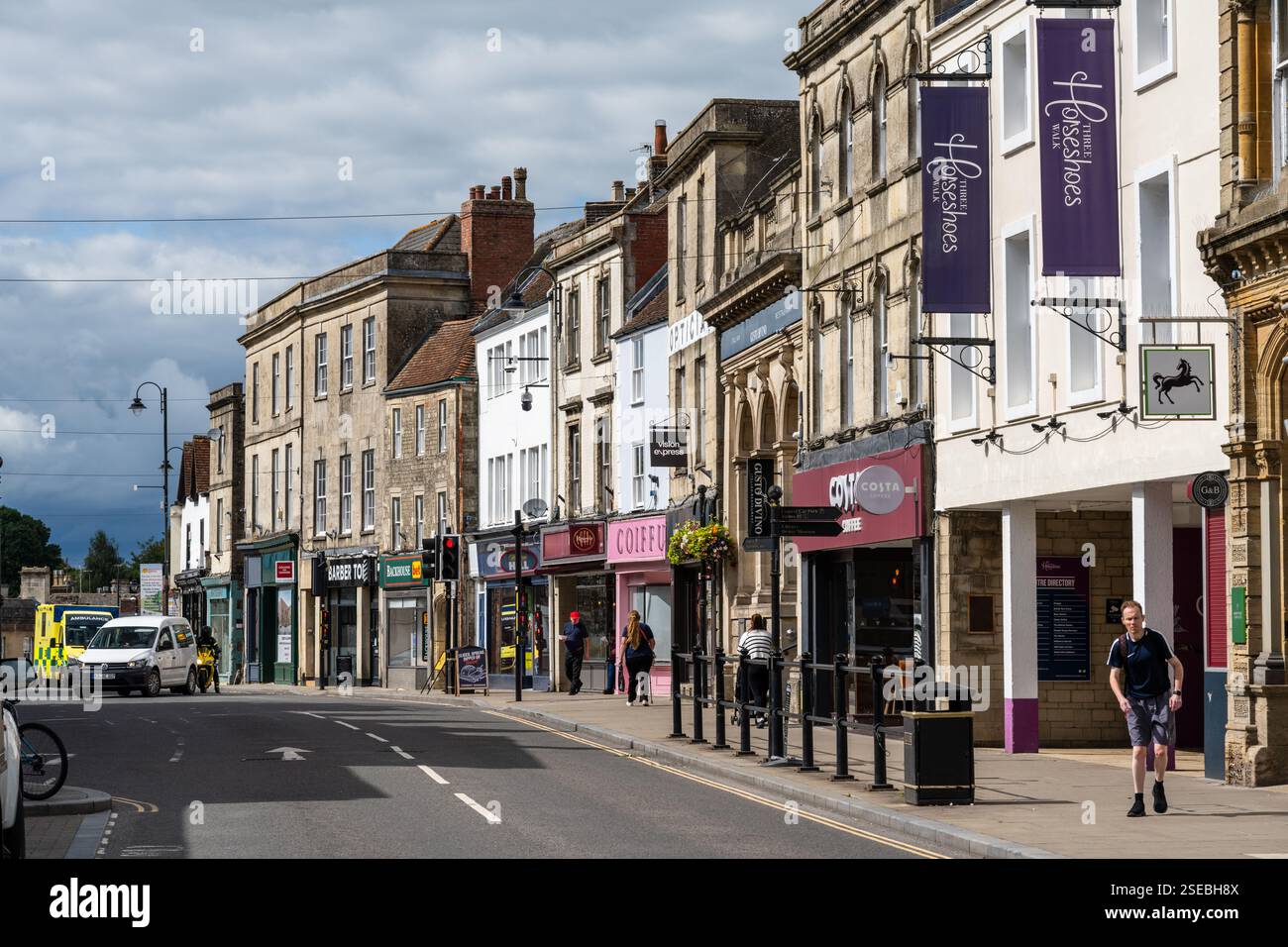 I pedoni passano accanto ai negozi della tradizionale High Street di Warminster nel Wiltshire. Foto Stock