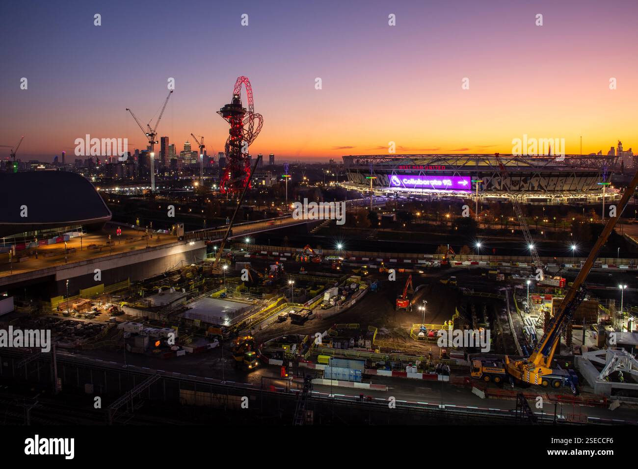 Il sole tramonta dietro il London Stadium e i lati dei lavori nel parco olimpico post-giochi di Stratford, East London. Foto Stock