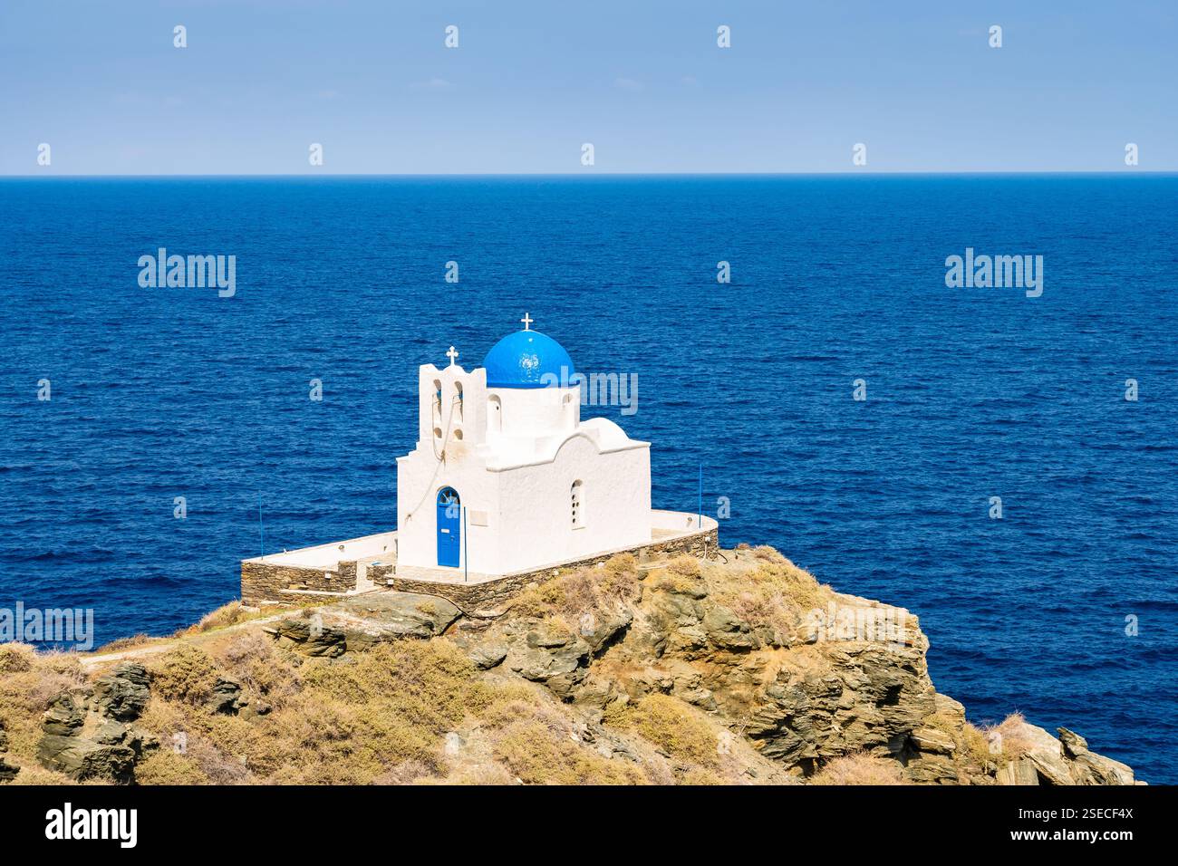 Vista della piccola chiesa costruita su rocce e del mare blu sullo sfondo nel villaggio di Kastro, sull'isola di Sifnos, in Grecia Foto Stock