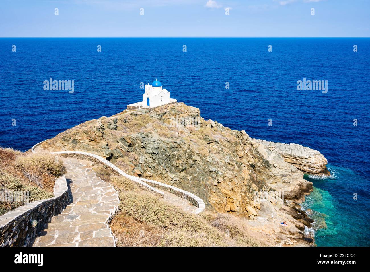 Sentiero costiero con scalini per una piccola chiesa costruita su rocce e mare blu sullo sfondo nel villaggio di Kastro, isola di Sifnos, Grecia Foto Stock