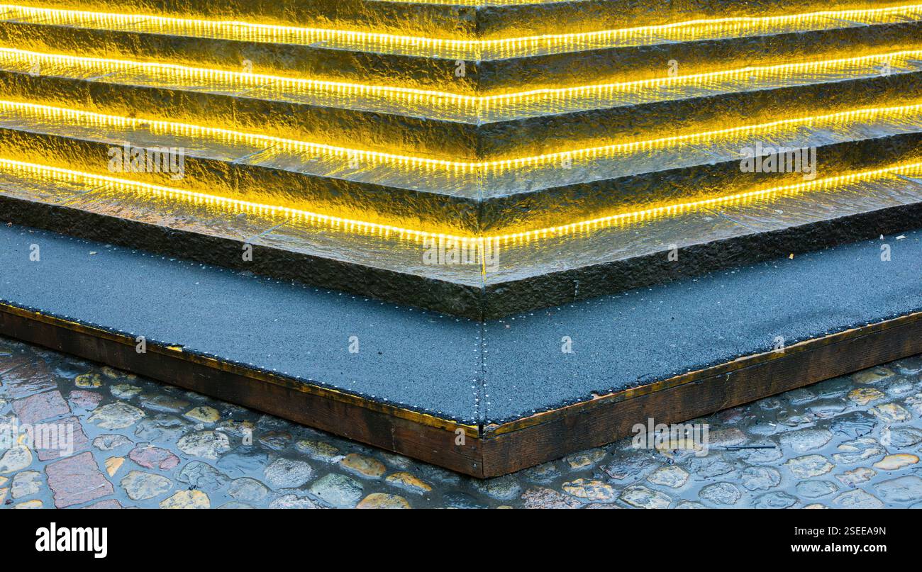 I bordi illuminati delle scale a LED mettono in risalto una struttura moderna contro i ciottoli. Foto Stock