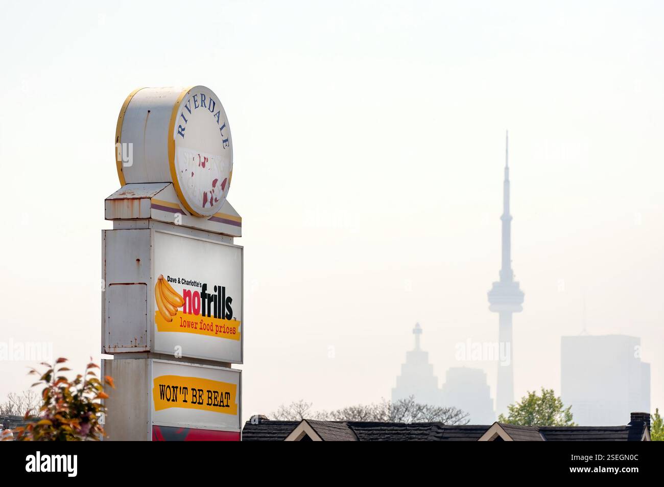 Toronto, Canada - 5 maggio 2011: L'insegna per il negozio di alimentari Riverdale No Frills in Carlaw Ave con lo skyline di Toronto sullo sfondo. Questa loca Foto Stock