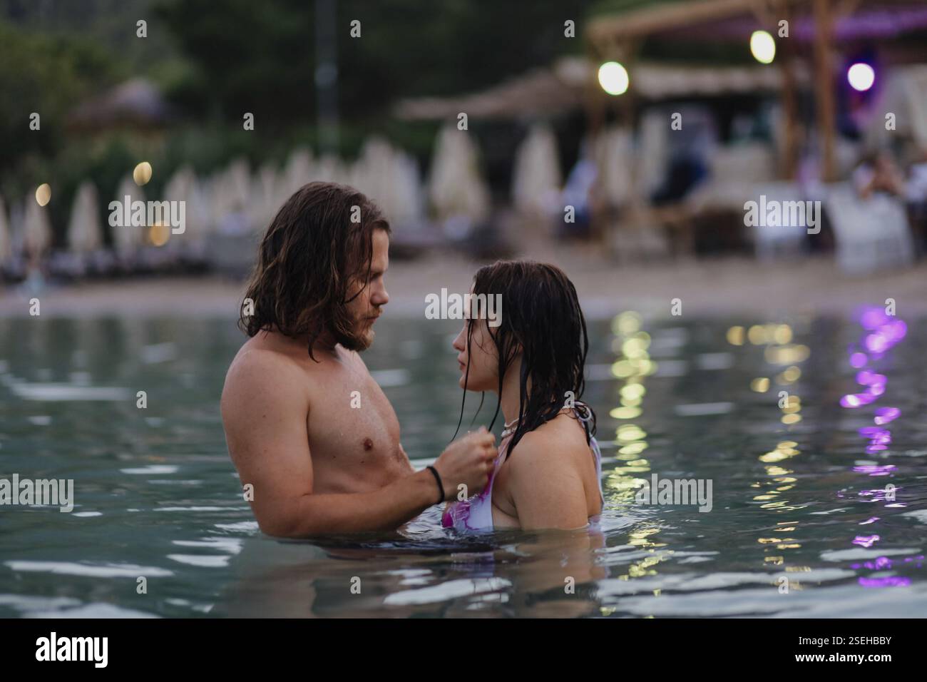 In coppia, osservando l'un l'altro intimamente, le luci bokeh migliorano l'atmosfera serale Foto Stock