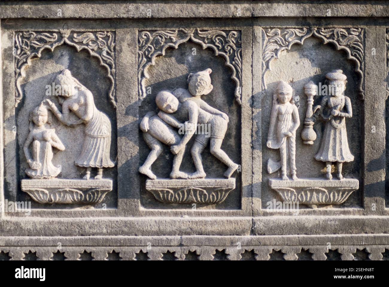 Rilievo o pannello di wrestler e scena del bagno uomo donna servo scolpito in pietra sul muro del tempio di Maheshwar, Maheshwar, Madhya Pradesh, India, Asia Foto Stock