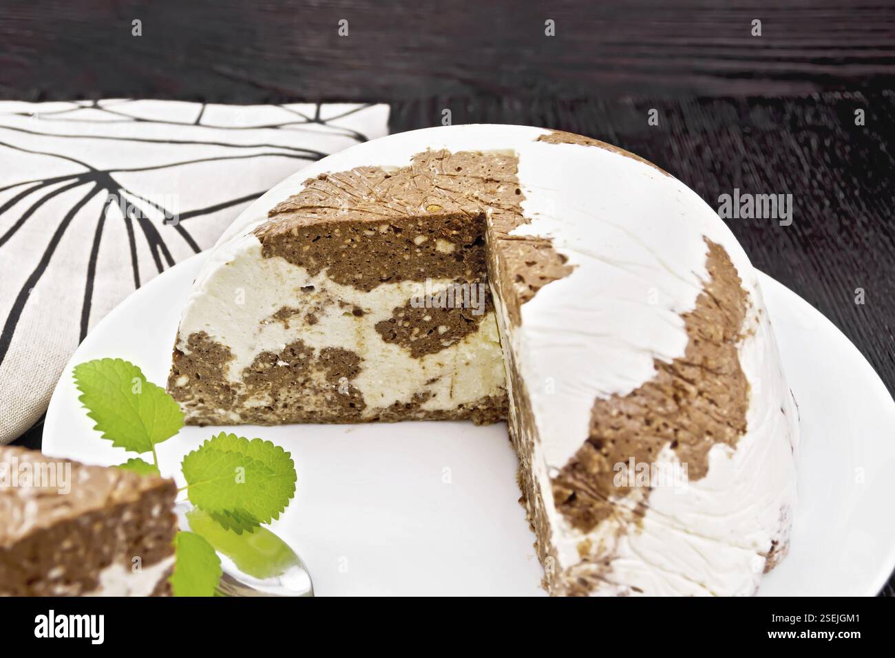 Dessert di ricotta e cacao con gelatina e zucchero in un piatto bianco, asciugamano e un cucchiaio su sfondo di legno Foto Stock