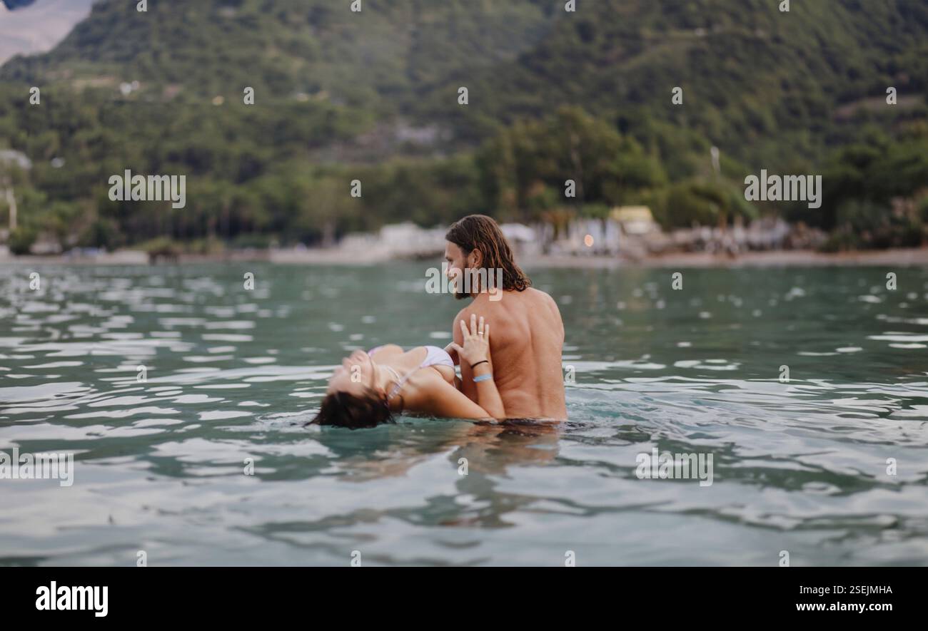 Un momento romantico con una coppia in acqua circondata da verdi colline Foto Stock