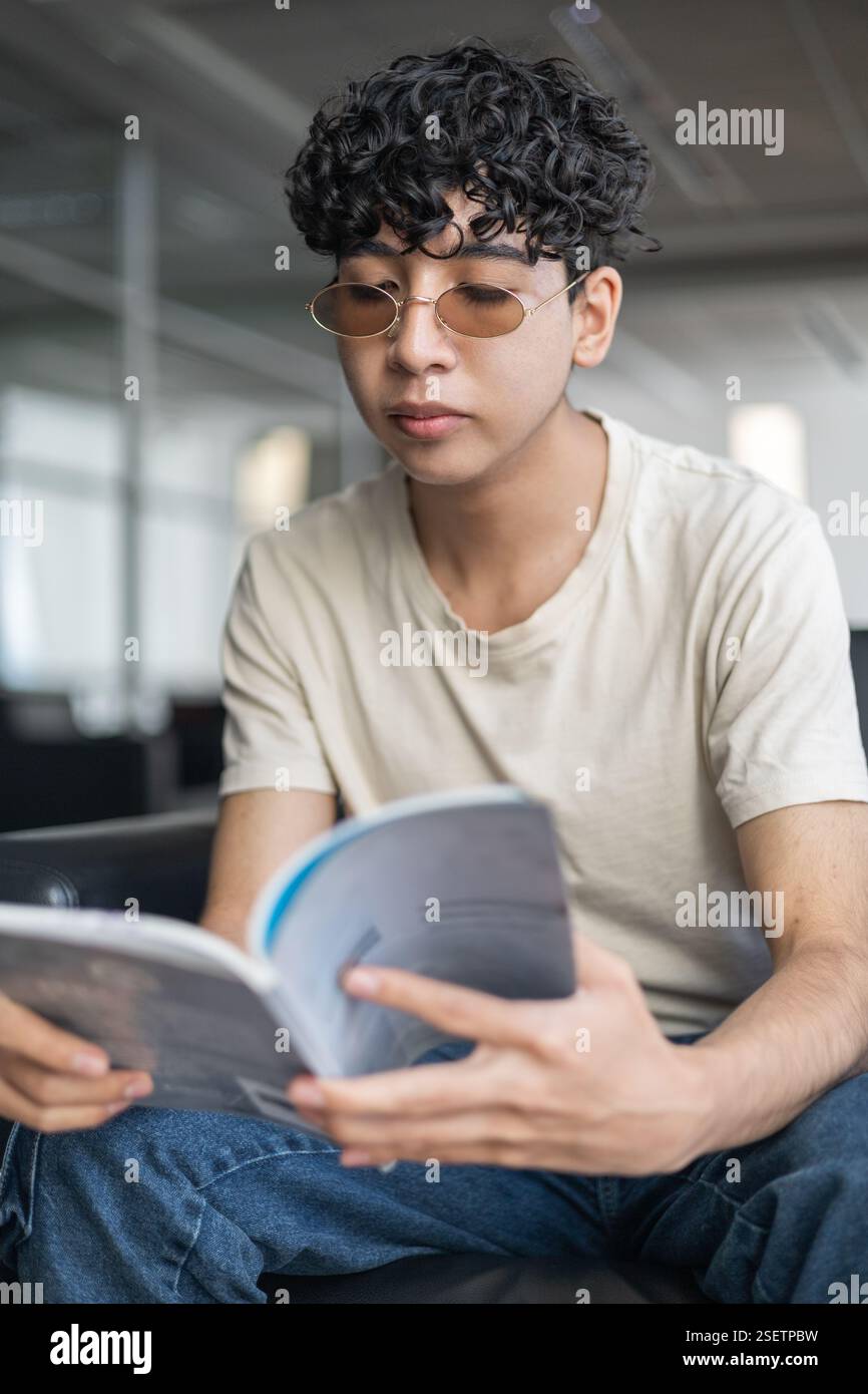 Una persona che legge un manuale per comprendere le istruzioni, concentrata sull'apprendimento. Ideale per i temi dell'istruzione, dell'autoapprendimento e della risoluzione dei problemi. Foto Stock