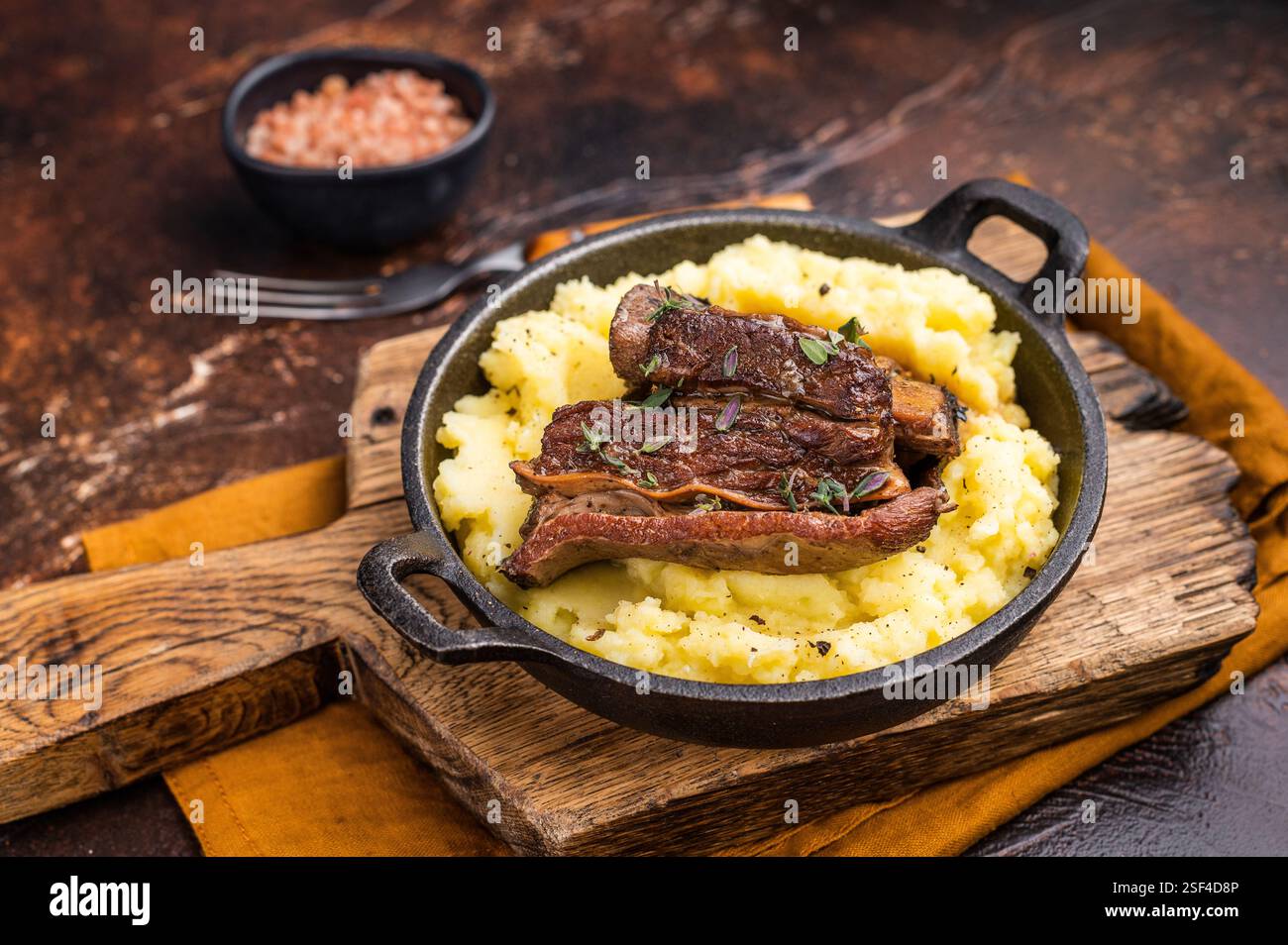 Primo piano di teneri costolette di manzo, splendidamente caramellate e riposate su un letto di cremoso purè di patate, creando un'invitante scena culinaria. marrone Foto Stock