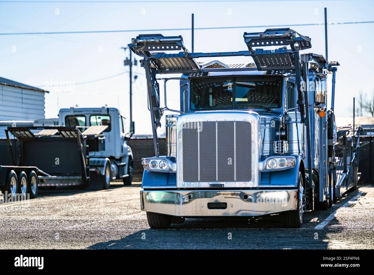Autocarro industriale blu per autocarri classici con cofano classico e semirimorchio idraulico modulare a due livelli vuoto in piedi all'interno del magazzino Foto Stock