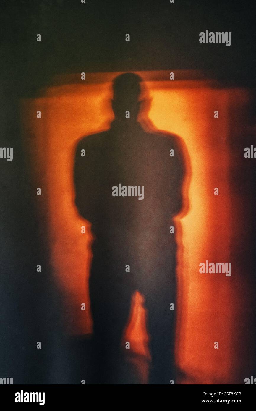 Silhouette di un uomo misterioso con sfondo rosso chiaro Foto Stock